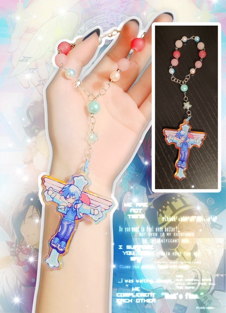 May include: A colorful beaded necklace with a charm featuring a cartoon character with blue hair and wings. The charm is shaped like a cross. The necklace is made of silver chain and has pink, white, and blue beads.