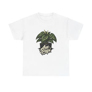 May include: White t-shirt featuring a graphic of a potted plant with large, dark green leaves. The plant is in a black square pot, with the words "Aye Papi" in a stylized font below the pot.