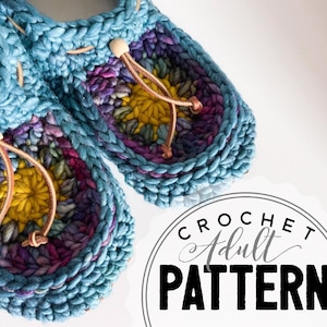 Peut inclure: Gros plan sur deux chaussons crochetés à la main, dans des tons de bleu, de violet et de jaune. Chaque chausson a une fermeture à cordon avec une perle en bois. L'image comprend le texte "CROCHET ADULT PATTERN".