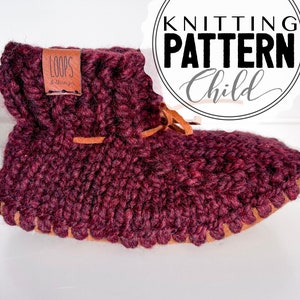 May include: Burgundy knitted slipper with a brown leather strap and a brown leather label that says "Loops & Things".
