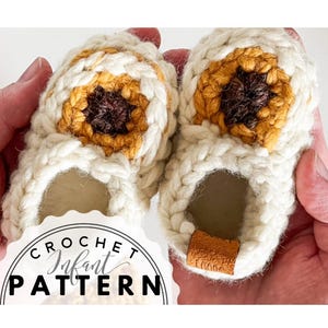 May include: Hand-crocheted baby booties in cream with a sunflower design. The centre of the sunflower is brown, surrounded by yellow and orange petals. The text "CROCHET Infant PATTERN" is displayed in a circular graphic.