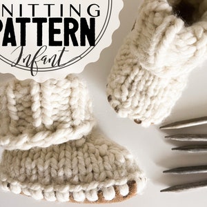 May include: A pair of white knitted baby booties with a fold-over cuff. The booties are made with a cable knit pattern and have a brown leather sole. The image also includes knitting needles.