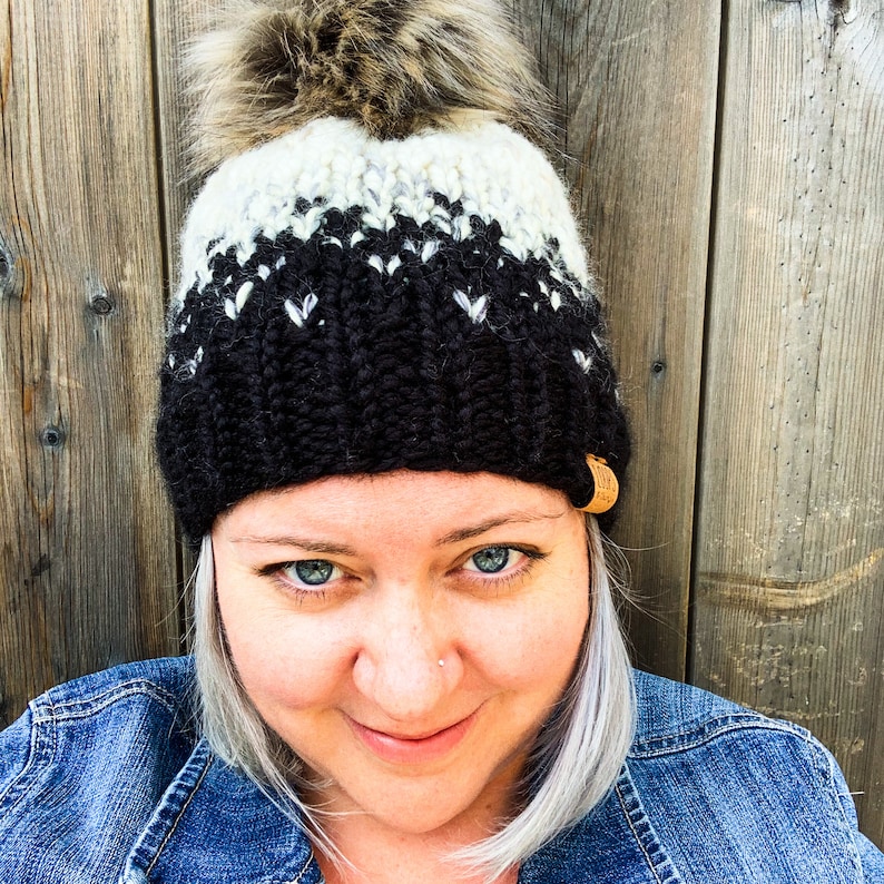 Puede incluir: Un gorro de punto negro y blanco con un pomp&oacute;n blanco. El gorro tiene una etiqueta de cuero negro en el lateral.
