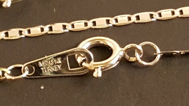 May include: A gold chain necklace with a lobster clasp and a tag that reads "MIDAS 14K TURKEY".