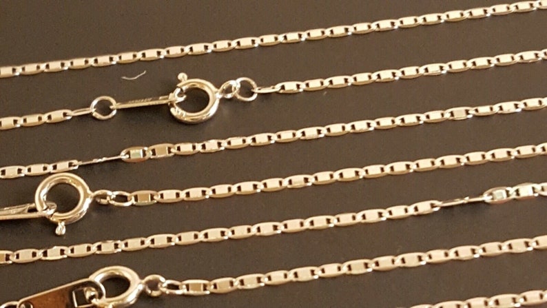 May include: Four silver chains with lobster claw clasps. The chains are made of small, rectangular links.