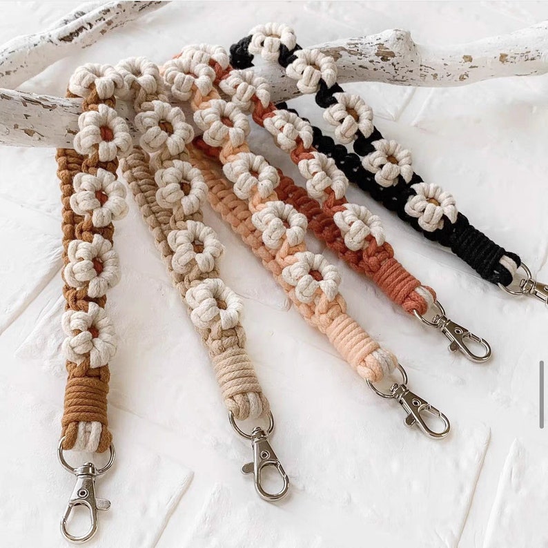 May include: Five crocheted keychains with daisy-shaped designs in brown, beige, peach, and black. Each keychain has a silver metal clasp.