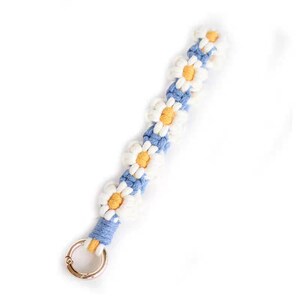 Puede incluir: Un llavero de crochet azul y blanco con un dise&ntilde;o de margarita y un anillo de metal dorado.