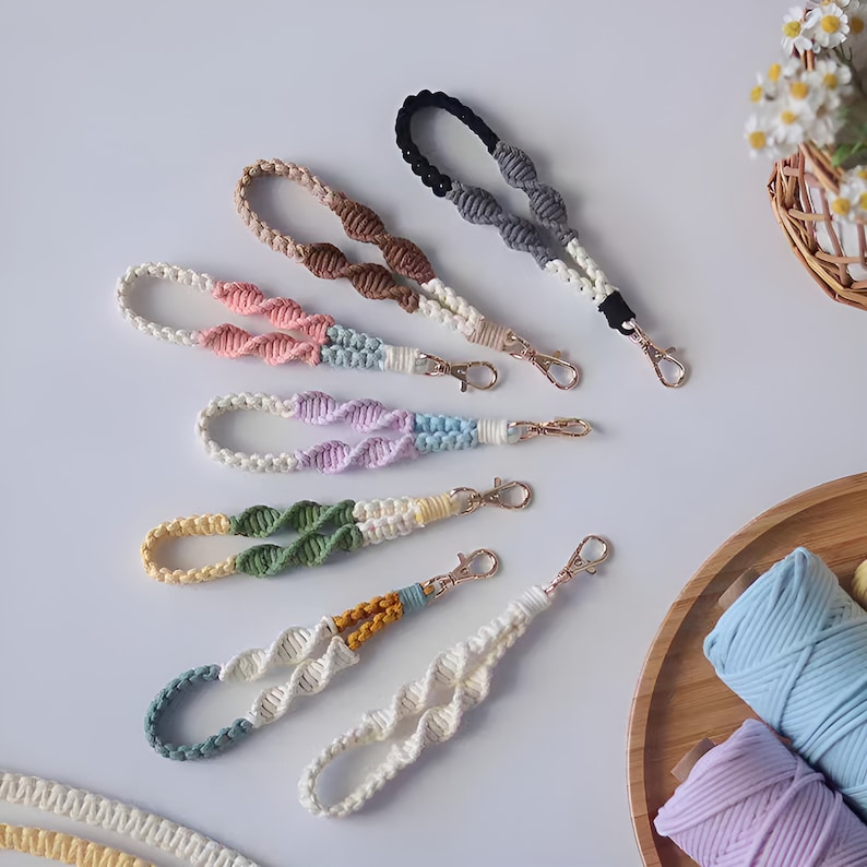 Pode incluir: Um conjunto de sete chaveiros coloridos, feitos &agrave; m&atilde;o e com n&oacute;s, com fechos dourados. Os chaveiros s&atilde;o feitos com uma variedade de cores, incluindo rosa, roxo, azul, verde, amarelo, castanho e cinzento.