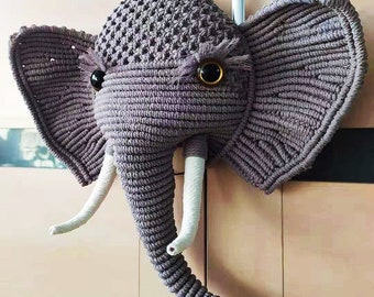 May include: A gray crocheted elephant head wall hanging with white yarn tusks and large black eyes.