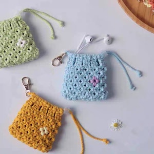 May include: Three crocheted pouches with drawstrings and small flower embellishments. The pouches are in green, blue, and yellow.