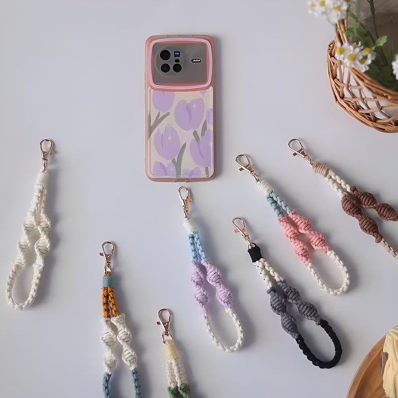 Pode incluir: Conjunto de pulseiras de telefone coloridas com designs de n&oacute;s. As pulseiras s&atilde;o feitas de cord&atilde;o tecido e apresentam v&aacute;rias cores, incluindo branco, marrom, rosa, azul, cinza e preto. Cada pulseira tem um fecho de metal dourado.