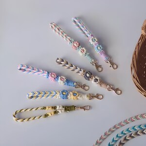 Pu&ograve; includere: Cinque portachiavi intrecciati colorati con ciondoli a forma di fiore. Ogni portachiavi ha una combinazione di colori diversa e una chiusura in metallo dorato.