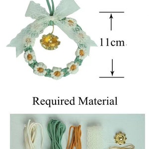 K&ouml;nnte beinhalten: Ein gr&uuml;ner und wei&szlig;er Kranz mit einer Glocke und einer wei&szlig;en Schleife aus Spitze. Der Kranz hat einen Durchmesser von 11 cm. Der Kranz ist aus Garn gefertigt und hat ein G&auml;nsebl&uuml;mchenmuster. Der Kranz ist von den Materialien umgeben, die f&uuml;r seine Herstellung ben&ouml;tigt werden, darunter Garn, Spitze und eine Glocke.