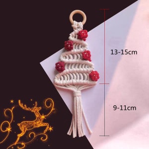 Op de afbeelding: Witte macram&eacute; kerstboom ornament met rode pompoenen en een houten ring aan de bovenkant. De ornament is 13-15 cm hoog en 9-11 cm breed.