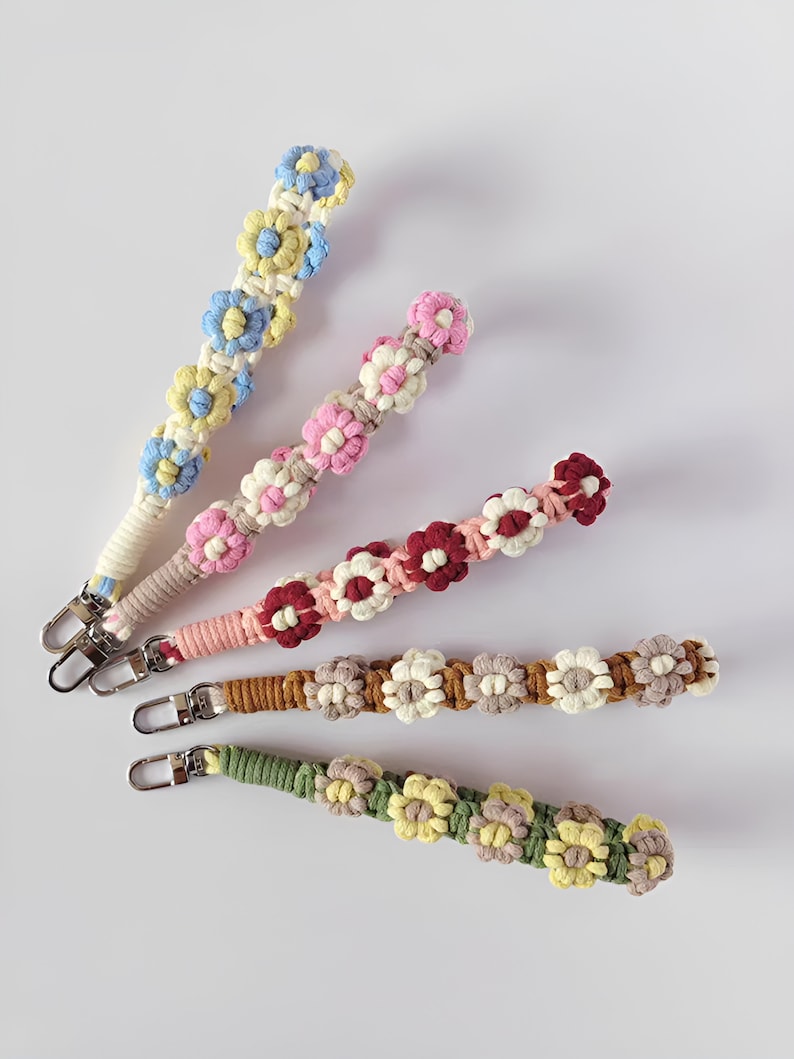 Może przedstawiać: Cztery kolorowe breloczki z kwiat&oacute;w na szydełku ze srebrnymi zapięciami. Breloczki są wykonane z przędzy w r&oacute;żnych kolorach i mają serię kwiat&oacute;w na szydełku.