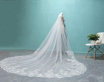 May include: A long, white bridal veil with a delicate lace trim. The veil is made of soft tulle and is perfect for a wedding ceremony.