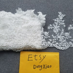 May include: Two pieces of white lace trim with floral designs. The lace is delicate and intricate. The trim is perfect for adding a touch of elegance to any project.