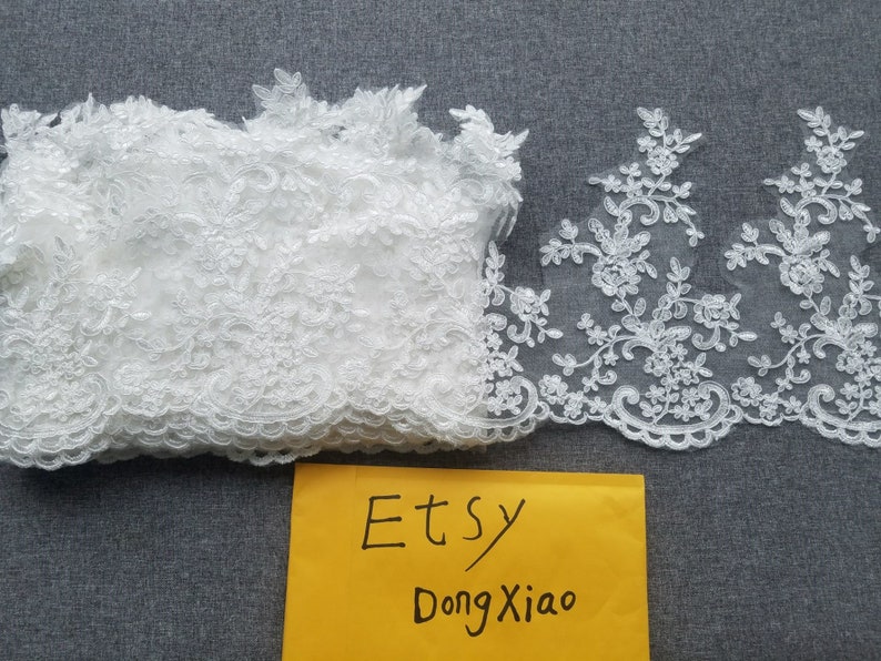 May include: Two pieces of white lace trim with floral designs. The lace is delicate and intricate. The trim is perfect for adding a touch of elegance to any project.