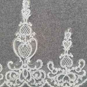 May include: White lace trim with a delicate floral pattern and sequins. The trim is approximately 6 inches wide.