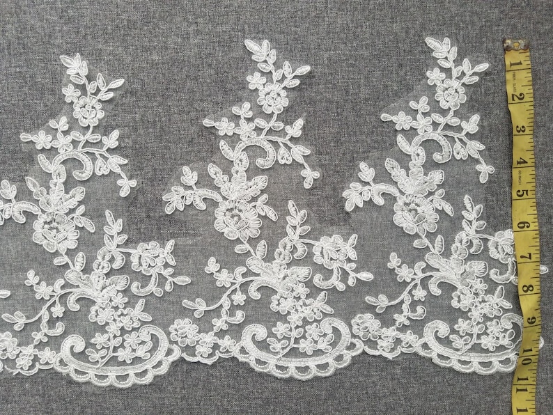 May include: White lace trim with a floral design. The lace is approximately 2 inches wide.