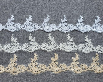 May include: Rows of delicate floral lace trim in white, ivory, and gold. The lace features a repeating pattern of flowers and leaves along a scalloped edge. Ideal for sewing, crafting, or adding a decorative touch to garments or home decor projects.