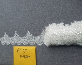 May include: White lace trim with sequins, featuring a scalloped edge. The trim is approximately 1.5 inches wide. The trim is shown on a gray surface with a yellow envelope that says "Etsy Dong Xiao".