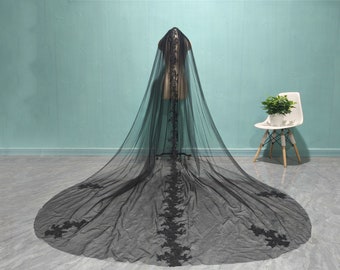 May include: A black tulle wedding veil with delicate floral lace embroidery. The veil is long and flowing, with a cathedral length.