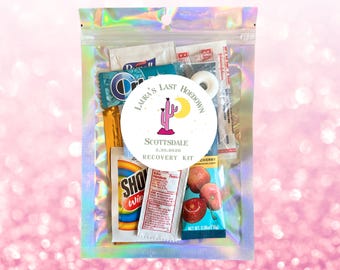 May include: A clear, iridescent plastic bag containing small items. A circular sticker with text and a cactus design is centered on the bag. The text reads "Laura's Last Hoedown, Scottsdale, 3.30.2020, Recovery Kit."