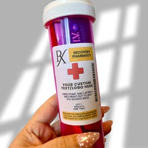 Puede incluir: Un frasco de receta rosa y morado con tapa blanca. La etiqueta dice "Recovery Pharmacy" e incluye espacio para texto personalizado. La botella también tiene un símbolo de cruz roja y el texto "Toma 1 después de una noche salvaje para ayudarte a recuperarte."