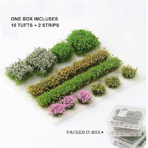 Può includere: Una collezione di cespugli e strisce modello in miniatura in vari colori, tra cui verde, giallo, bianco e rosa. Il testo "ONE BOX INCLUDES 10 TUFTS + 2 STRIPS" è visibile. Gli articoli sono confezionati in un contenitore di plastica trasparente.