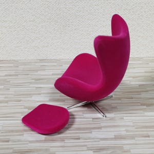 Pu&ograve; includere: Una sedia a forma di uovo rosa brillante con un poggiapiedi abbinato. La sedia ha una base cromata e ruota.