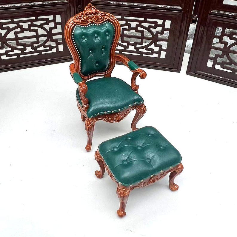 May include: A green upholstered armchair with ornate wooden legs and a matching green footstool. The chair and footstool have a tufted design.