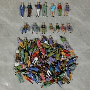 May include: A collection of miniature plastic figures representing people in various poses and colorful outfits. The set includes several standing and seated figures arranged in rows, with a large, dense pile of mixed figures below them.