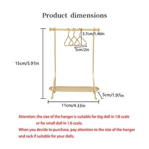 May include: A gold-colored metal doll clothing rack with three matching hangers. The rack measures 5.91 inches in height, 4.33 inches in width, and 1.97 inches in depth. Each hanger is 2 inches wide and 1.46 inches tall. Text indicates 1:8 or 1:6 scale.