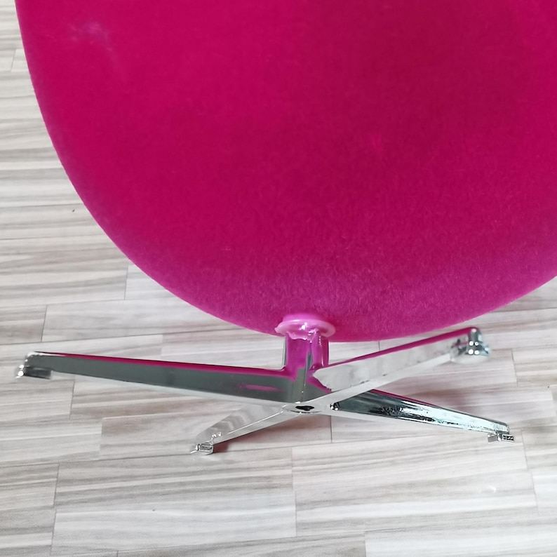 Pu&ograve; includere: Una sedia a forma di uovo rosa brillante con una base cromata. La sedia &egrave; realizzata in un tessuto morbido e soffice e ha un design elegante e moderno.