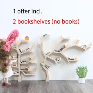 Op de afbeelding: Twee miniatuur houten boekenplanken in de vorm van bomen met takken als planken. De planken zijn gevuld met miniatuurboeken. De planken bevinden zich op een witte muur. 1 aanbod incl. 2 boekenplanken (zonder boeken)