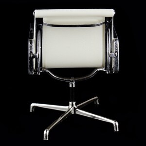 May include: A white office chair with a chrome frame and a star-shaped base. The chair is designed in a mid-century modern style.