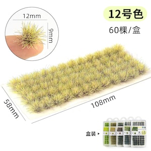 May include: A rectangular patch of model grass, measuring 108mm x 58mm, with a sample held by a finger, measuring 12mm x 9mm. The grass is a mix of light and dark green, with a yellow-brown hue. The packaging includes multiple grass patches.