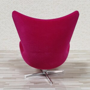 Pu&ograve; includere: Una sedia a forma di uovo di colore rosa brillante con una base girevole in cromo. La sedia &egrave; rivestita in un tessuto morbido e soffice.