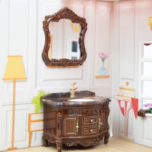 May include: A brown wooden vanity with a marble countertop and a gold tap. The vanity has two drawers and a cabinet door with intricate carvings. A mirror with a brown wooden frame hangs above the vanity.