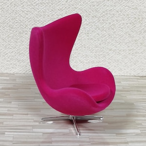 Pu&ograve; includere: Una sedia a forma di uovo di colore rosa brillante con una base girevole. La sedia &egrave; rivestita in un tessuto morbido e soffice.