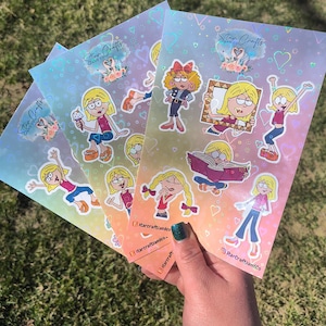 May include: Four sheets of holographic sticker paper with colorful cartoon illustrations of girls with pigtails, hearts, and the text "Star Crafts and Co."