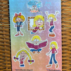May include: A set of six holographic stickers featuring cartoon girls with different expressions and poses. The stickers are on a rainbow background with hearts. The text "Star Crafts and Co." is at the top of the sheet.