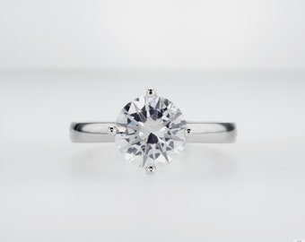 May include: A silver ring with a large, clear, round diamond.