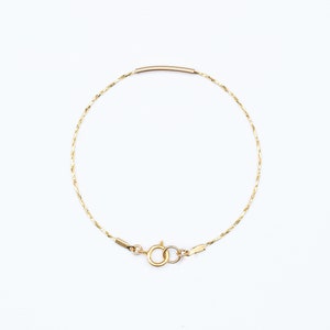 May include: A delicate gold chain bracelet with a simple bar clasp.