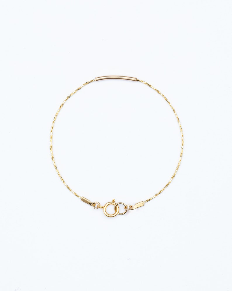 May include: A delicate gold chain bracelet with a simple bar clasp.