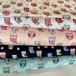 Könnte beinhalten: Stapel von Stoffen mit einem sich wiederholenden Muster aus bunten Eulen. Die Eulen sind in verschiedenen Posen und Farben dargestellt, darunter Rosa, Blau und Gelb, vor weißen, pfirsichfarbenen, marineblauen und hellblauen Hintergründen. Kleine Gänseblümchen-Akzente sind ebenfalls vorhanden.