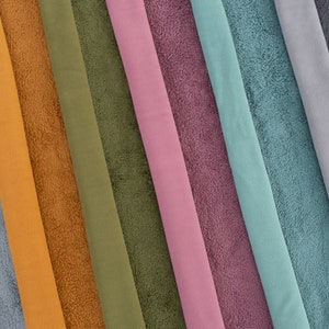 Pu&ograve; includere: Una collezione di campioni di tessuto in vari colori, tra cui grigio scuro, grigio chiaro, blu, turchese, rosa, viola, arancione, marrone e verde. Il tessuto ha una texture morbida e soffice.