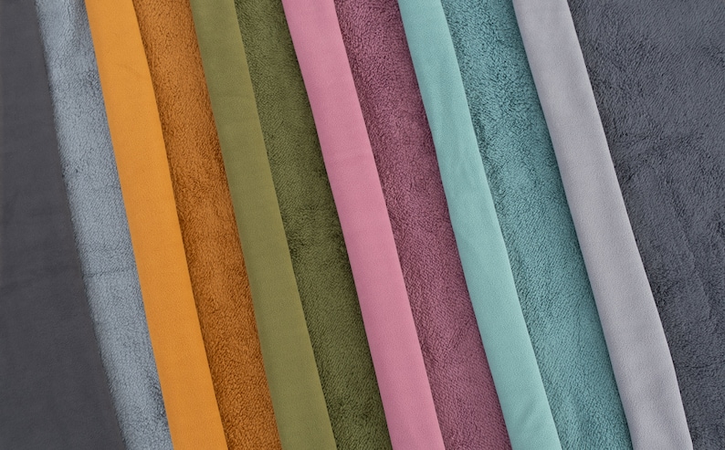 Pu&ograve; includere: Una collezione di campioni di tessuto in vari colori, tra cui grigio scuro, grigio chiaro, blu, turchese, rosa, viola, arancione, marrone e verde. Il tessuto ha una texture morbida e soffice.