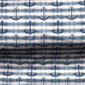 May include: A white and blue striped fabric with a repeating pattern of navy blue anchors. The fabric has a tie-dye effect.